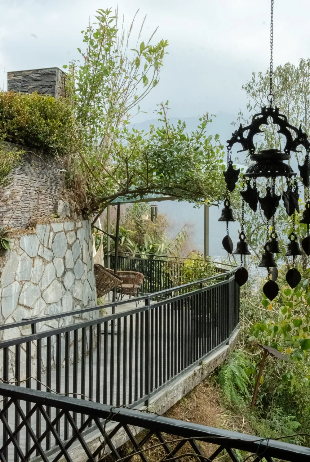 Stone-walled garden walkway with hanging bells at Green Hamlet