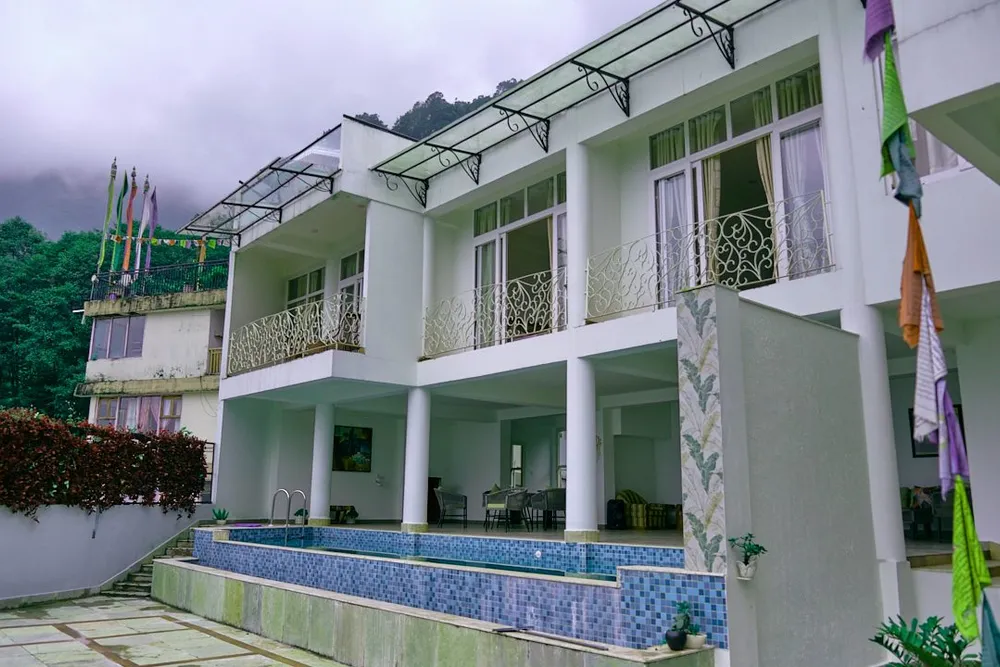 White villa with balconies beside the pool at Kunjham Retreat